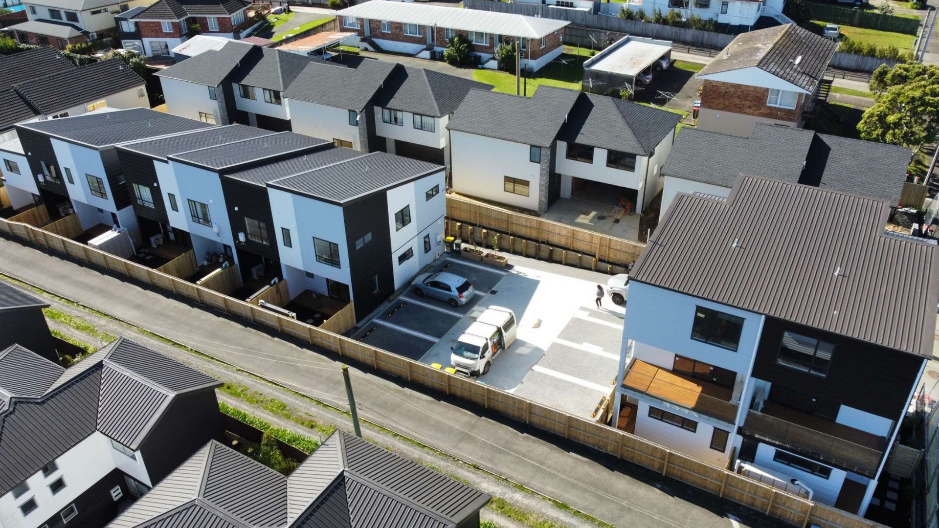 Aerial view of residential neighborhood with modern townhouses and parking area.
