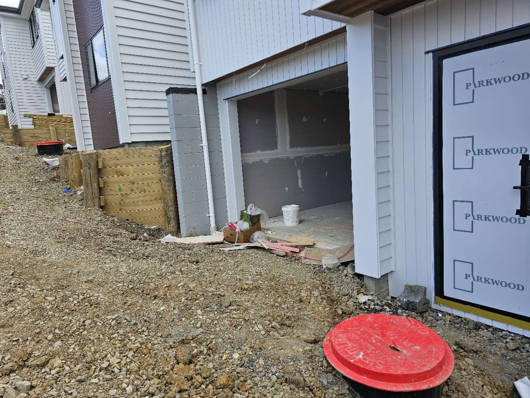 Construction site of a townhouse with unfinished garage and sloped gravel pathway.